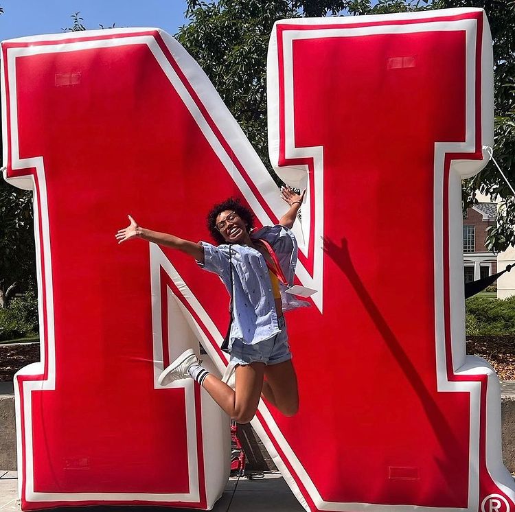 A young woman posing in front of the UNL N logo