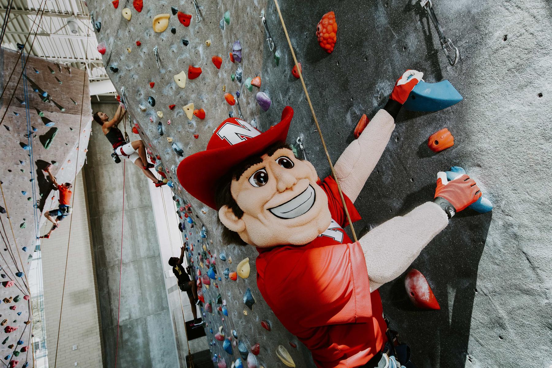 Herbie Husker climbs the climbing wall in the Outdoor Adventures Center