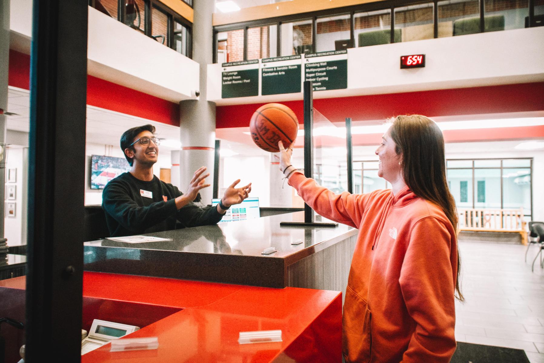 Student returns basketball to the front desk at the Campus Recreation Center