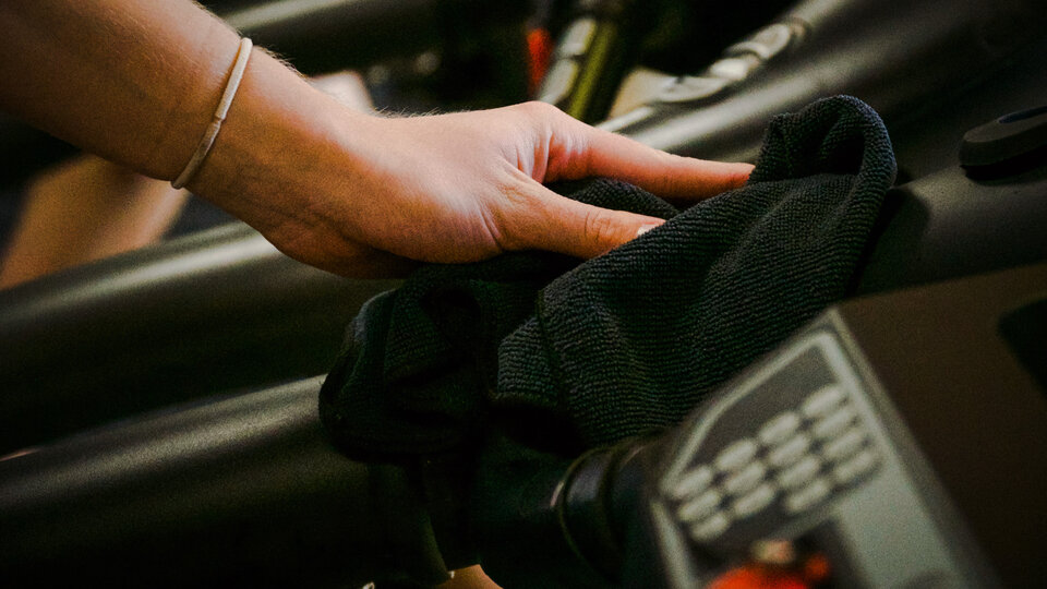 person cleaning equipment with towel