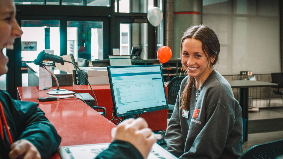 student at front desk smiling