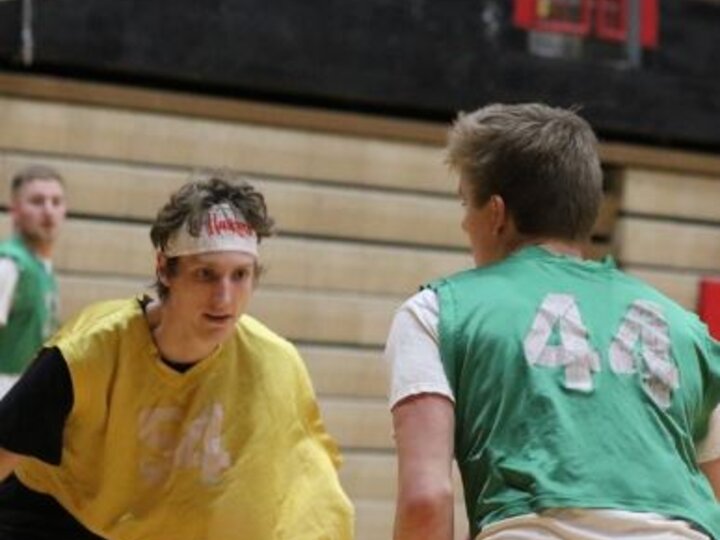 Two basketball players in green and yellow jerseys face off on a court.