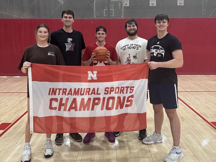 Students holding basketball and championship flag at the basketball court.