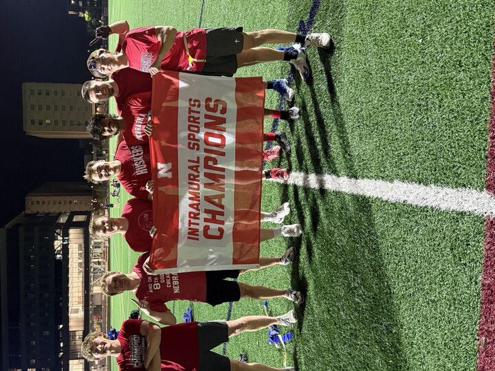 Seven people on a sports field holding a banner that reads "Intramural Sports Champions."