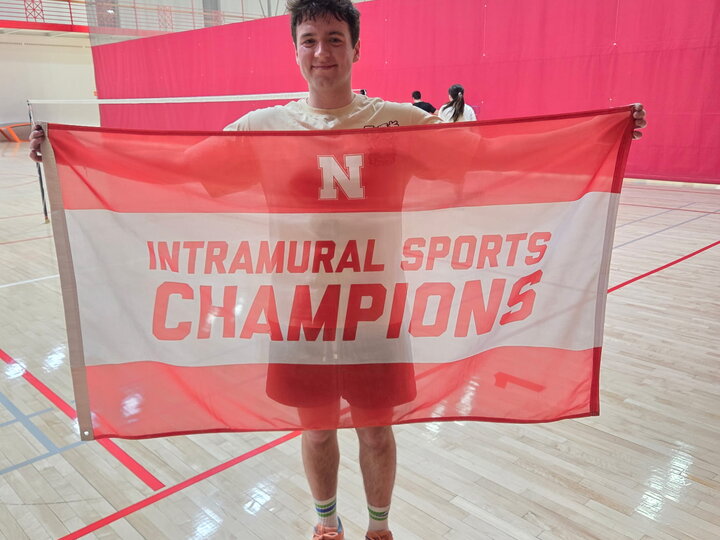 Red and white banner reading "Intramural Sports Champions" held in a gymnasium.
