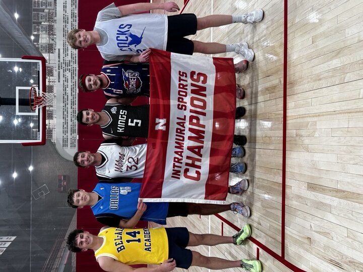 Six men on a gym court holding a red banner reading "Intramural Sports Champions."