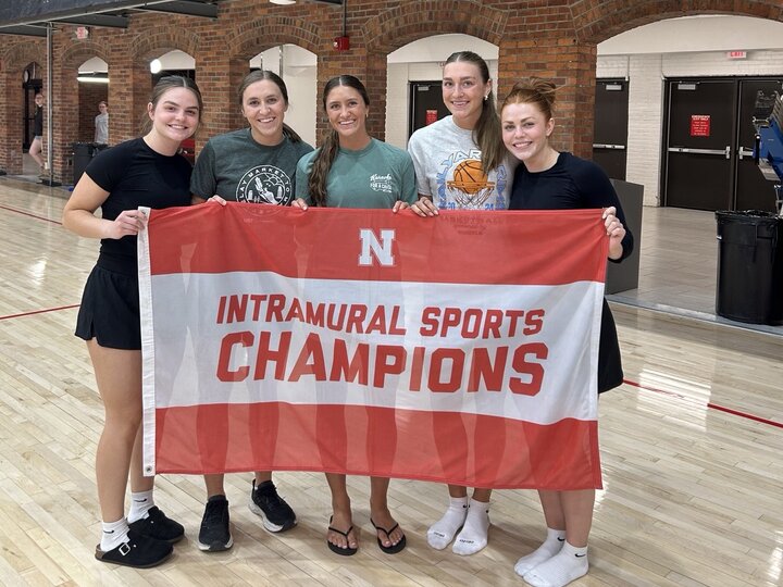 Group holding a red and white "Intramural Sports Champions" banner in a gymnasium.