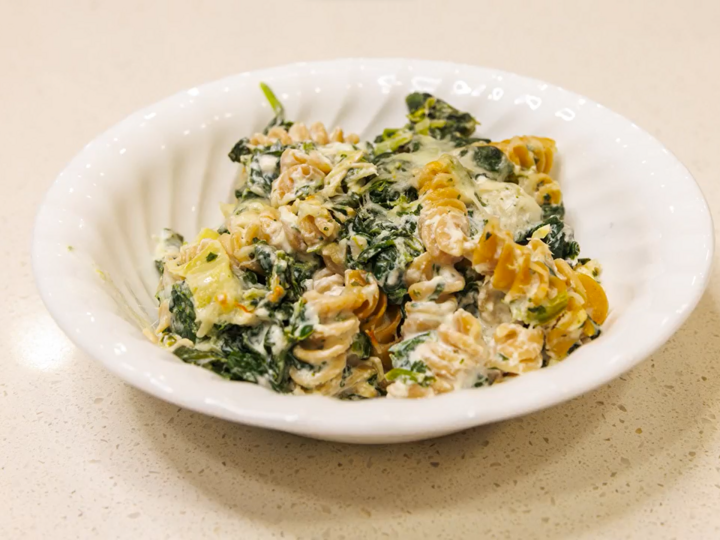 Chicken, Spinach, and Artichoke Pasta Bake is served in a white bowl