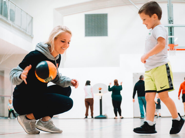 little kid playing basketball with a staff member