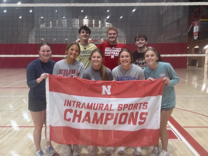 Group holding "Intramural Sports Champions" banner on a volleyball court.