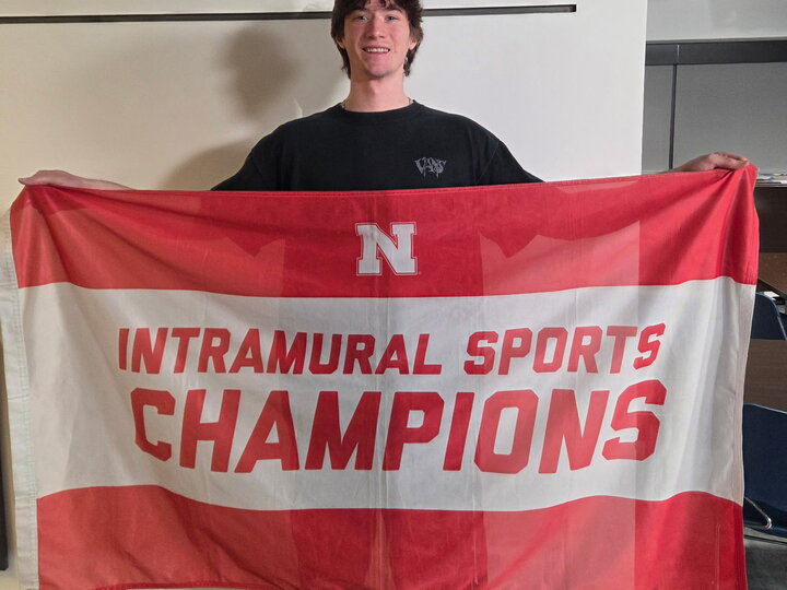 Red and white banner reading "Intramural Sports Champions" held indoors.