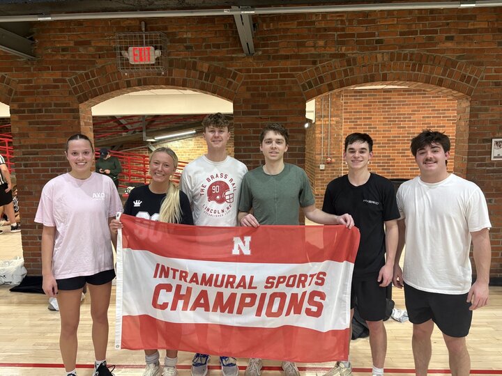 Group holding a red banner reading "Intramural Sports Champions" in a gym setting.
