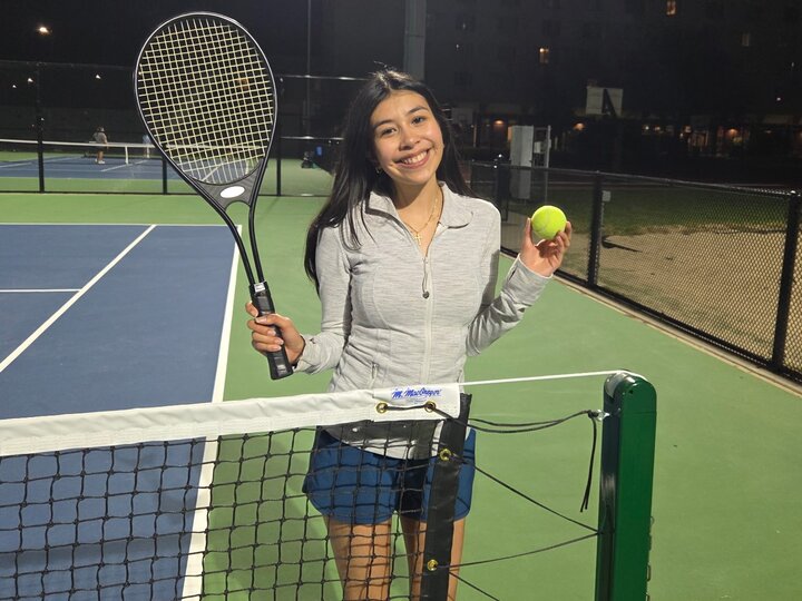 Woman holding tennis racket and tennis ball at tennis court.