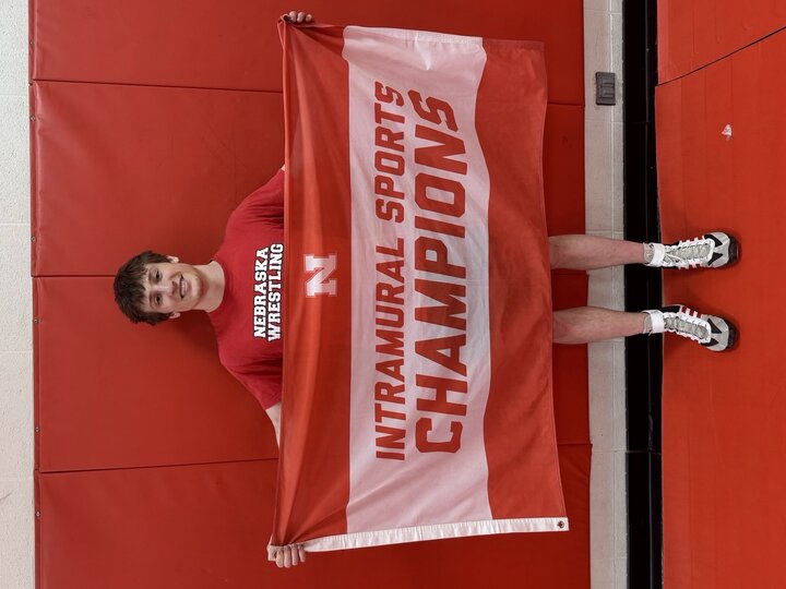 Boy holding a red and white "Intramural Sports Champions" banner against a red wall.