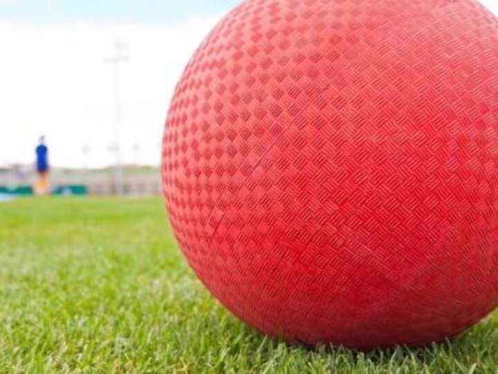 A red textured kickball on green grass.