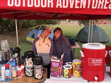 two people smiling at a festival under a tent.