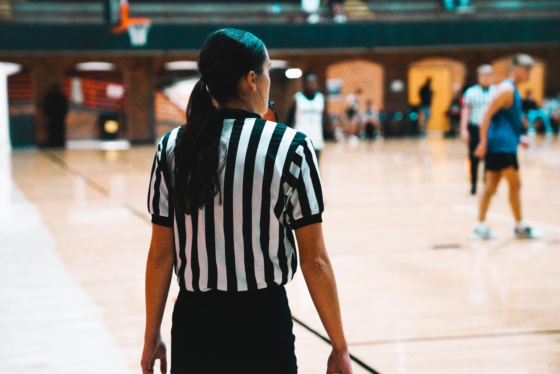 Basketball official looks on to a basketball game in the coliseum