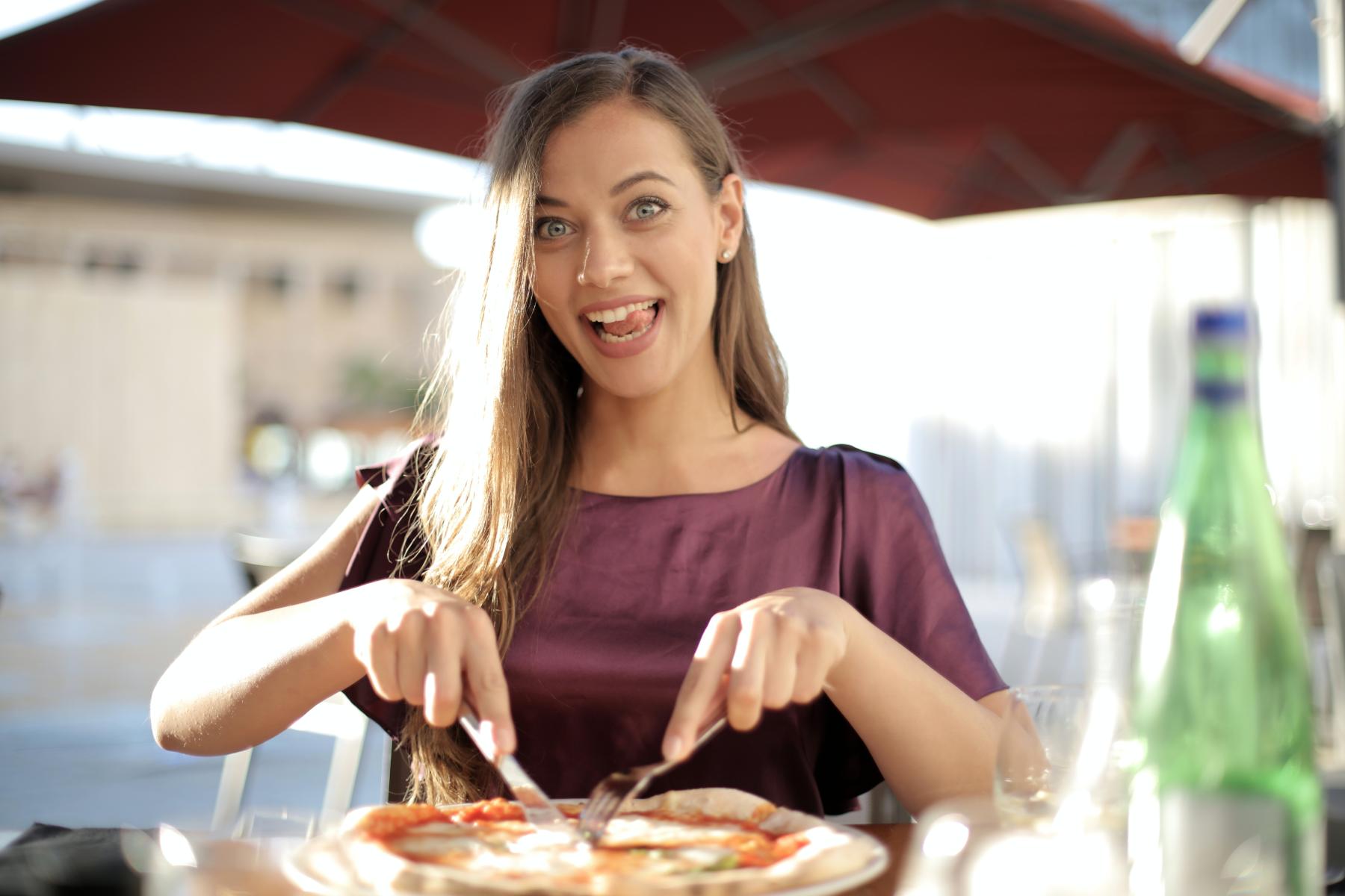 Eating a pizza in an outdoor cafe.