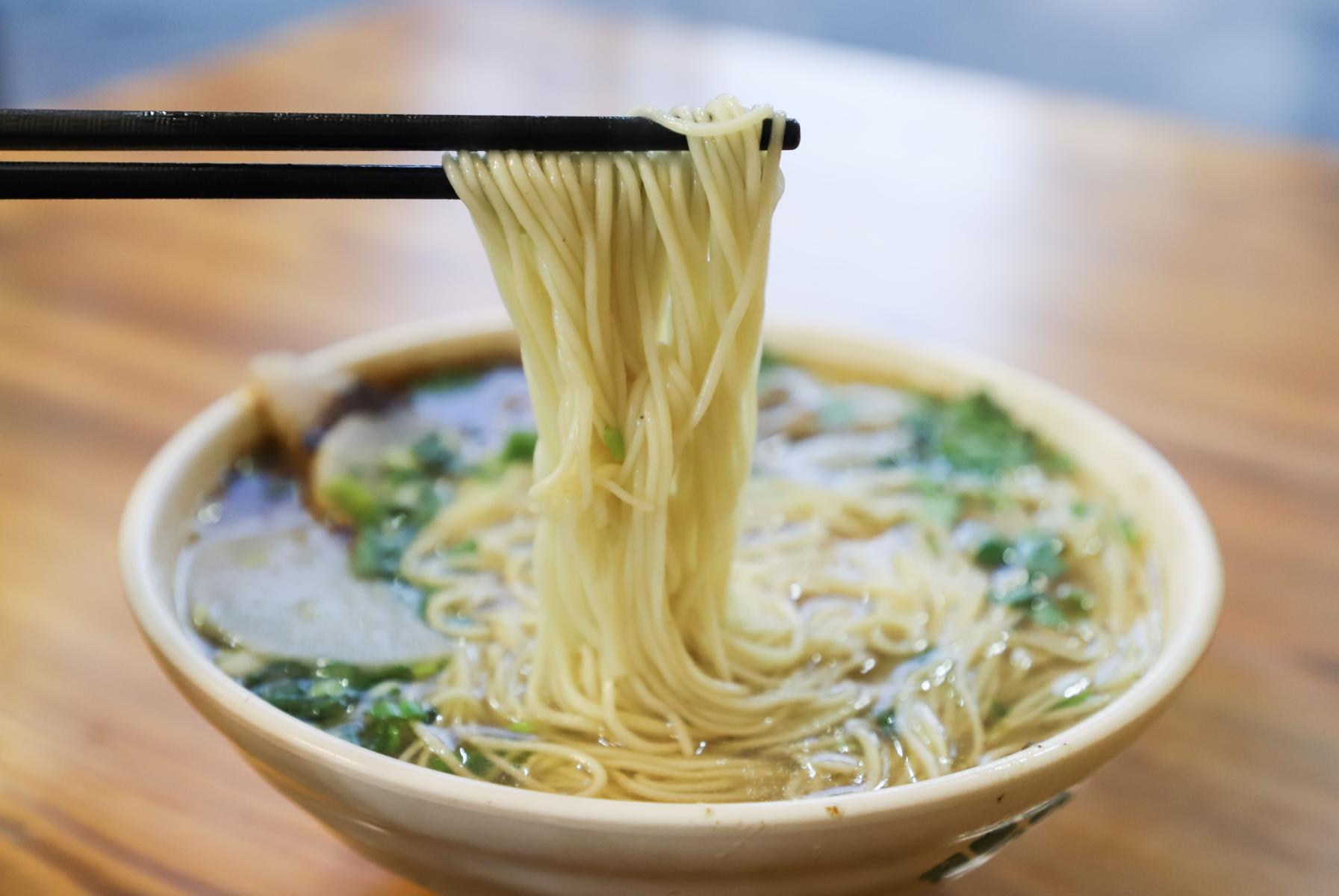 Chopsticks pull ramen noodles from a bowl