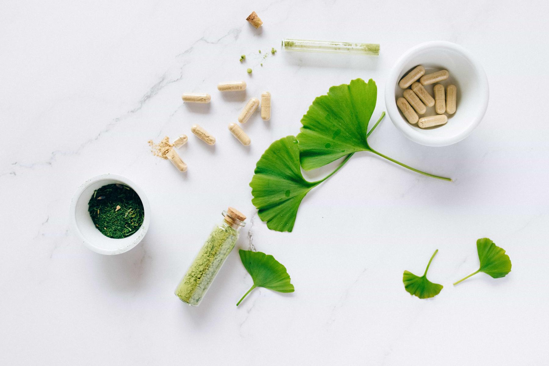 Leaves are ground up in a bowl next to pill capsules