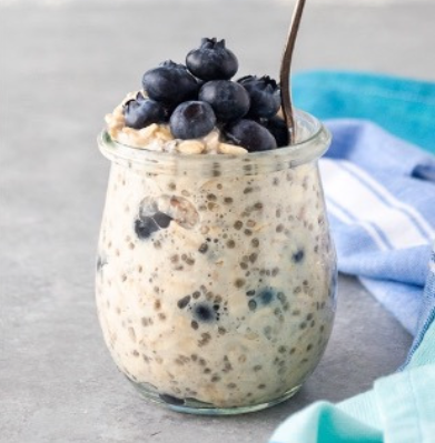 Blueberry overnight oats in a glass jar with a spoon.