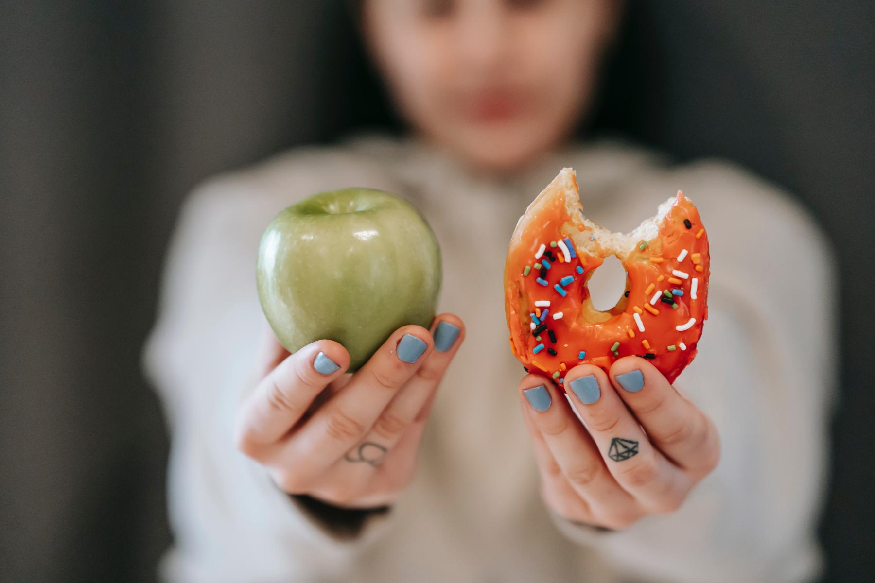 Person holding up an apple and a donut