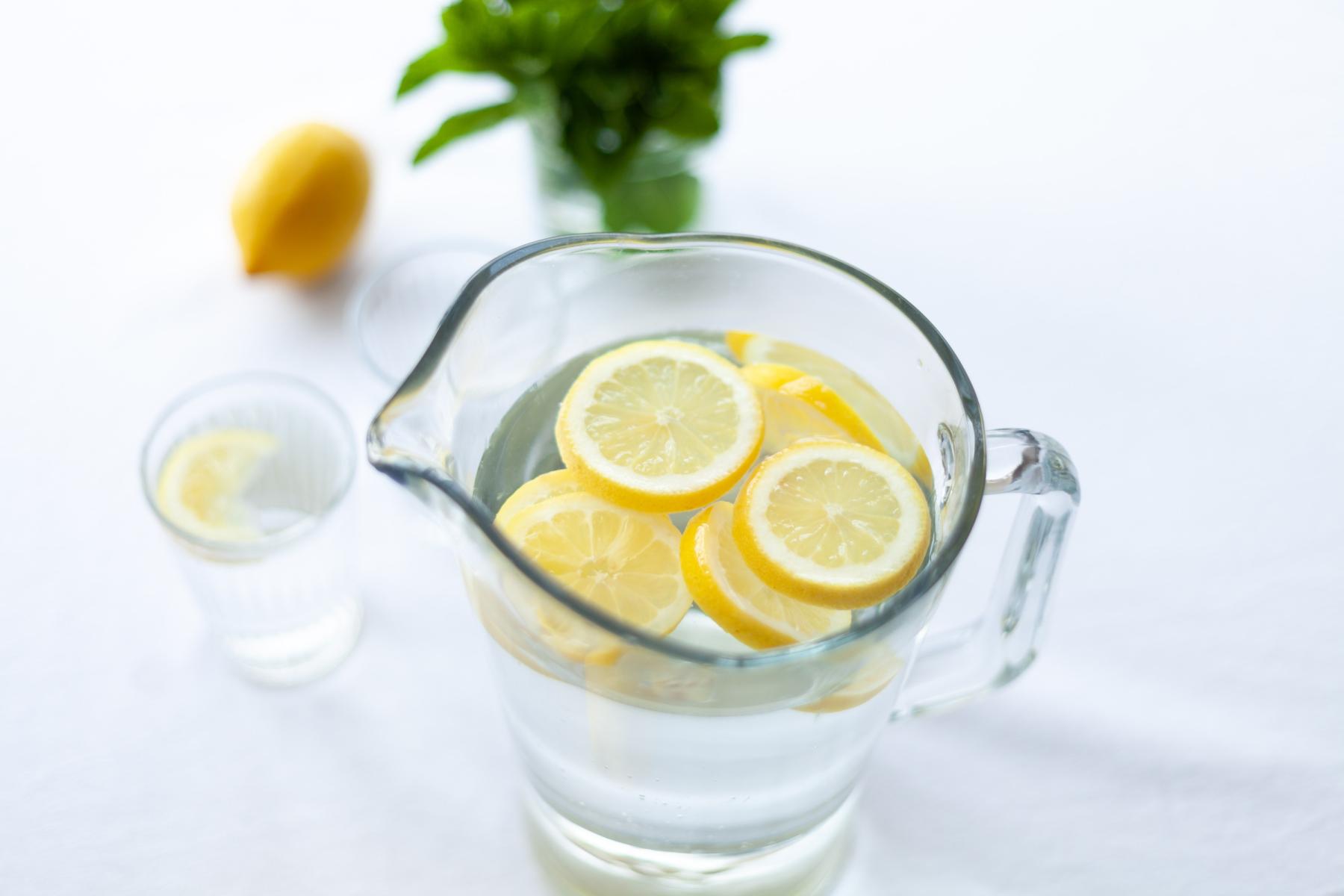 A pitcher of water in a glass jug with lemon slices floating on top